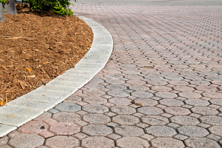 curved low angle brick paver driveway with mulch pile